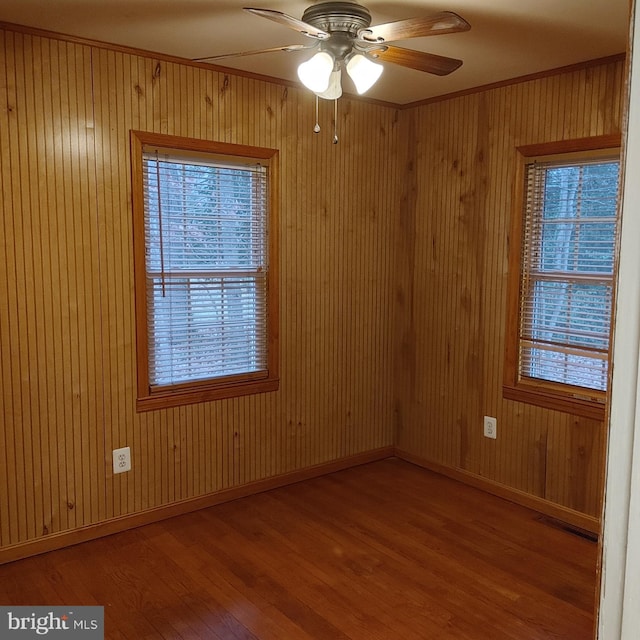 unfurnished room featuring ceiling fan, hardwood / wood-style floors, and wooden walls