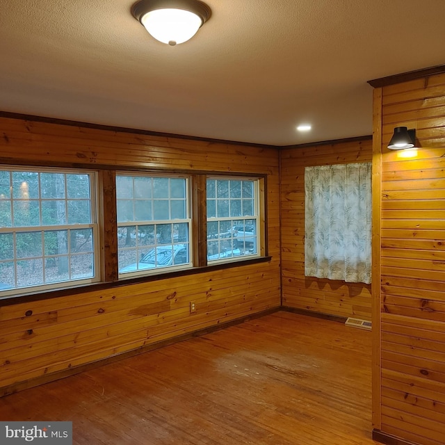 spare room featuring wood walls and hardwood / wood-style flooring