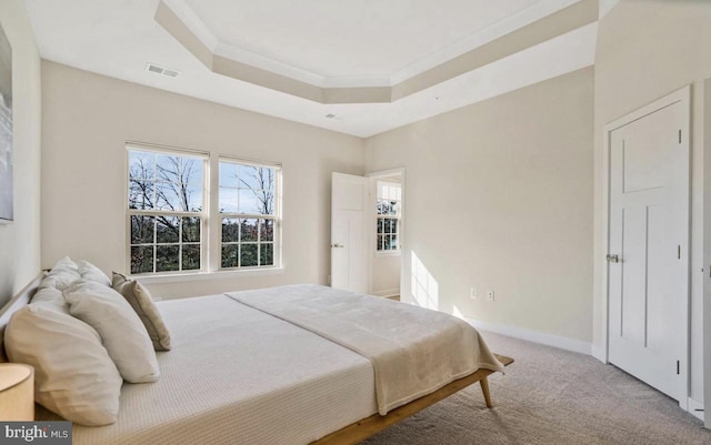 carpeted bedroom with a raised ceiling and crown molding