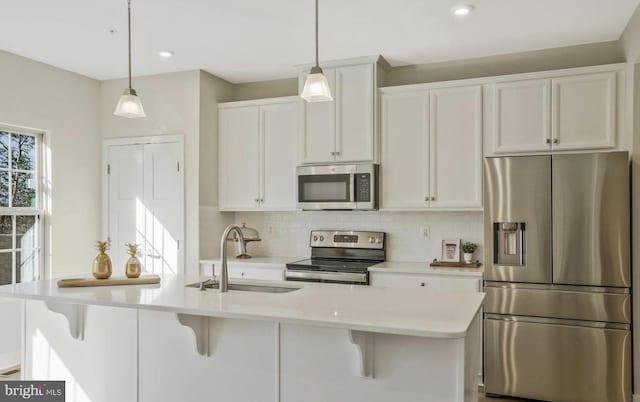 kitchen featuring pendant lighting, sink, stainless steel appliances, and a center island with sink