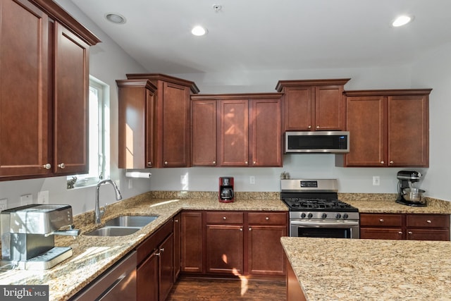 kitchen featuring light stone countertops, appliances with stainless steel finishes, dark hardwood / wood-style floors, and sink