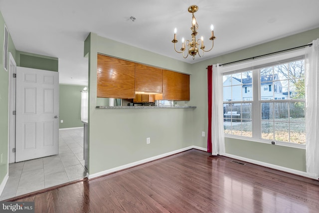 kitchen with kitchen peninsula, plenty of natural light, a chandelier, and light wood-type flooring