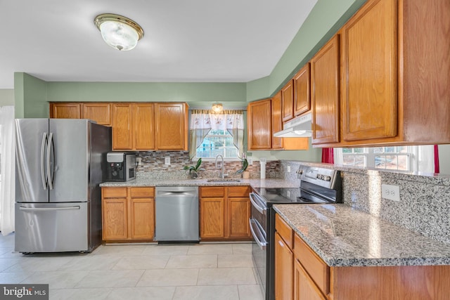 kitchen with sink, light stone countertops, light tile patterned floors, tasteful backsplash, and stainless steel appliances