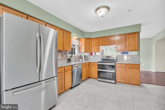 kitchen featuring light tile patterned flooring, light stone counters, sink, and appliances with stainless steel finishes