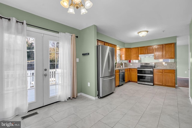 kitchen featuring light stone counters, french doors, appliances with stainless steel finishes, and a chandelier