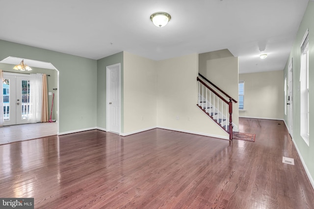 unfurnished living room featuring hardwood / wood-style floors, an inviting chandelier, and french doors