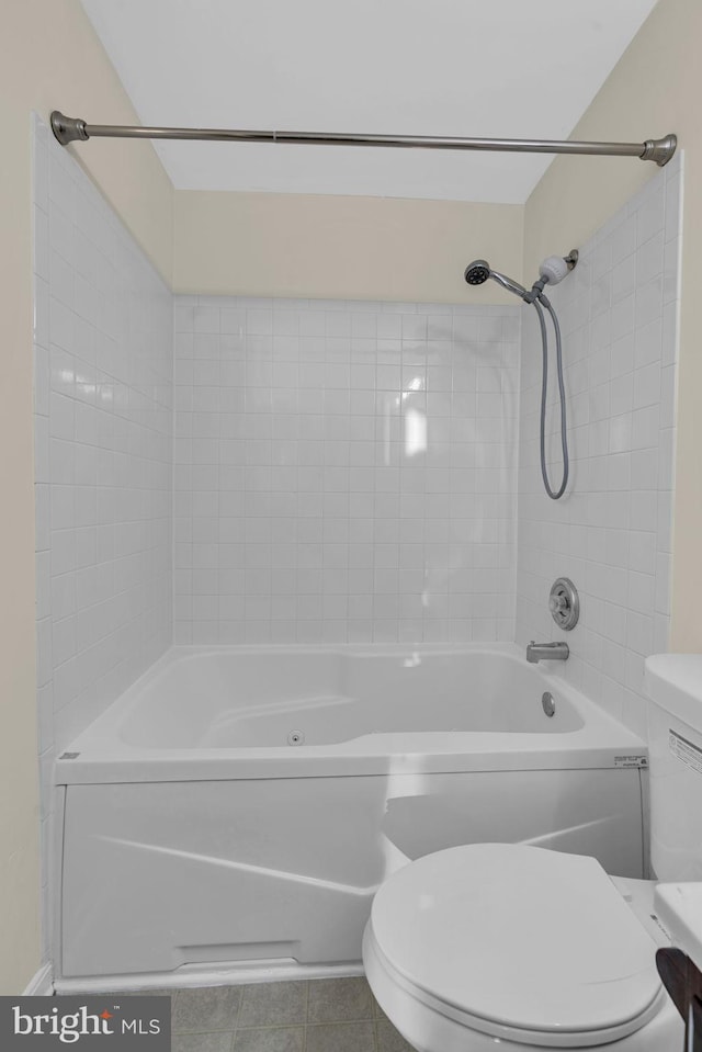 bathroom featuring toilet, tile patterned floors, and tiled shower / bath