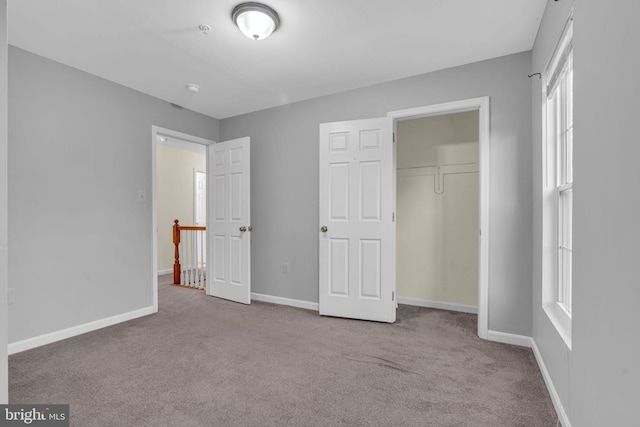 unfurnished bedroom with light colored carpet and a closet