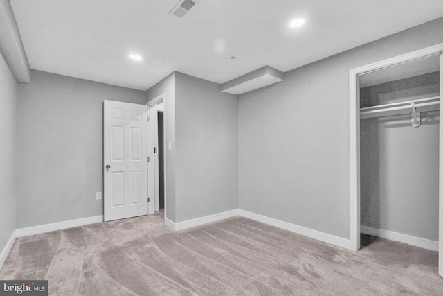 unfurnished bedroom featuring light colored carpet and a closet