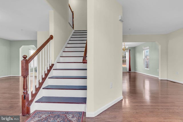 staircase with hardwood / wood-style flooring and an inviting chandelier