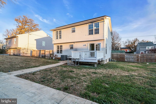 back of property with a deck, a yard, and central AC