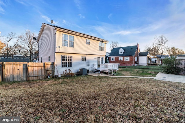 rear view of property featuring central air condition unit, a yard, and a deck