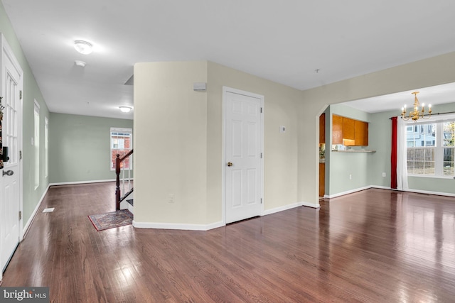 unfurnished living room featuring a chandelier and dark wood-type flooring