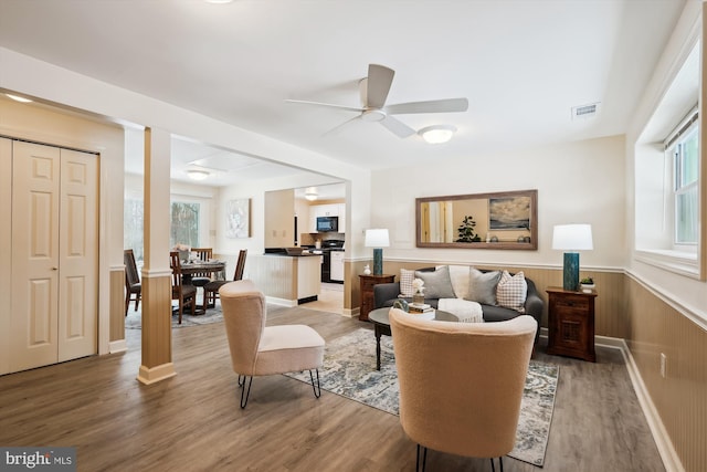 living room with ceiling fan, hardwood / wood-style floors, and wooden walls