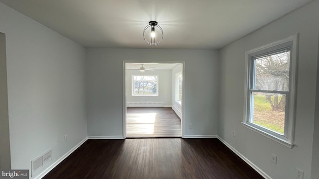 unfurnished room featuring dark hardwood / wood-style floors, ceiling fan, and a baseboard radiator