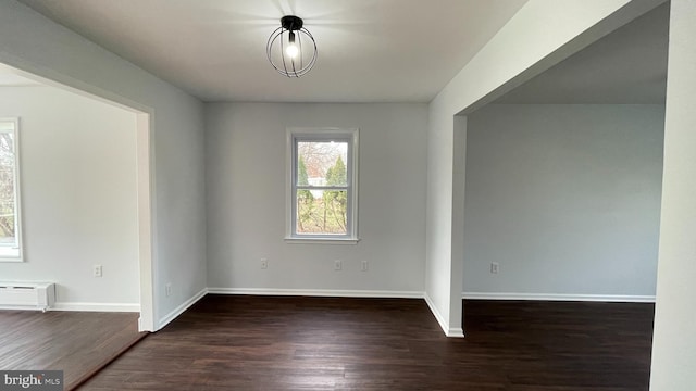 unfurnished room featuring dark hardwood / wood-style floors and a baseboard radiator