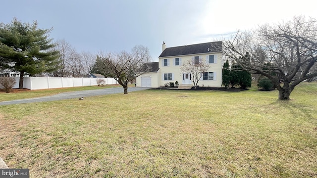 colonial house featuring a front yard and a garage