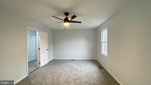 empty room featuring ceiling fan and carpet