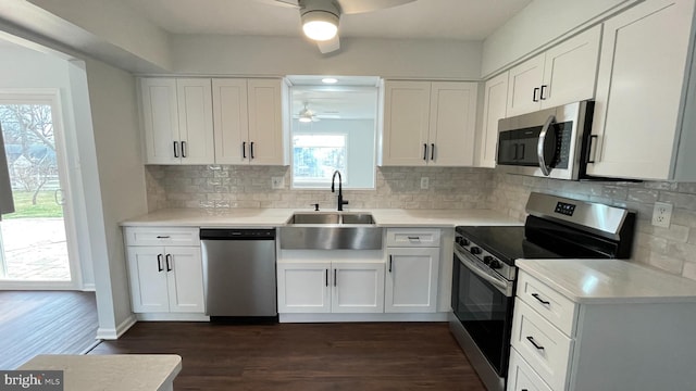 kitchen featuring decorative backsplash, stainless steel appliances, sink, white cabinets, and dark hardwood / wood-style floors