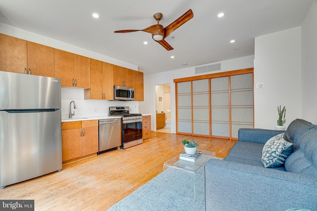 kitchen featuring visible vents, appliances with stainless steel finishes, open floor plan, light wood-type flooring, and a sink