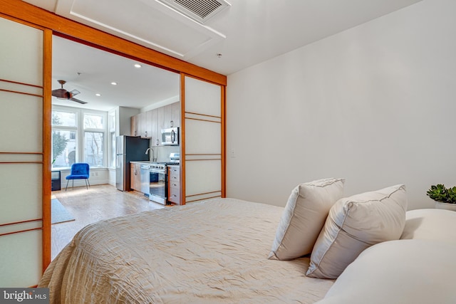 bedroom with freestanding refrigerator, visible vents, a sink, and recessed lighting