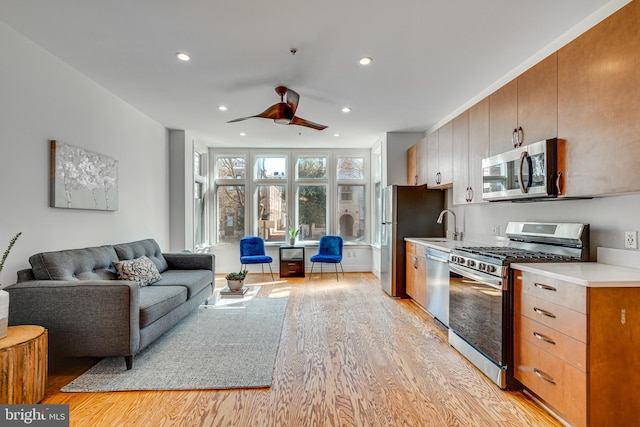 kitchen featuring recessed lighting, light countertops, light wood-style flooring, appliances with stainless steel finishes, and open floor plan