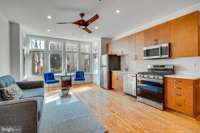 kitchen featuring open floor plan, stainless steel appliances, light countertops, light wood-style floors, and recessed lighting