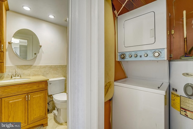 clothes washing area with sink, tile walls, stacked washer / dryer, and water heater