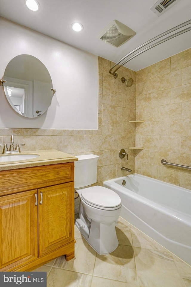 full bathroom featuring vanity, tiled shower / bath combo, tile walls, tile patterned flooring, and toilet