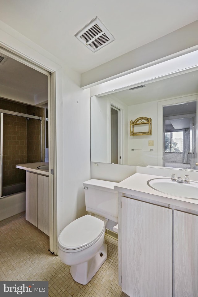 bathroom with tile patterned flooring, vanity, toilet, and an enclosed shower