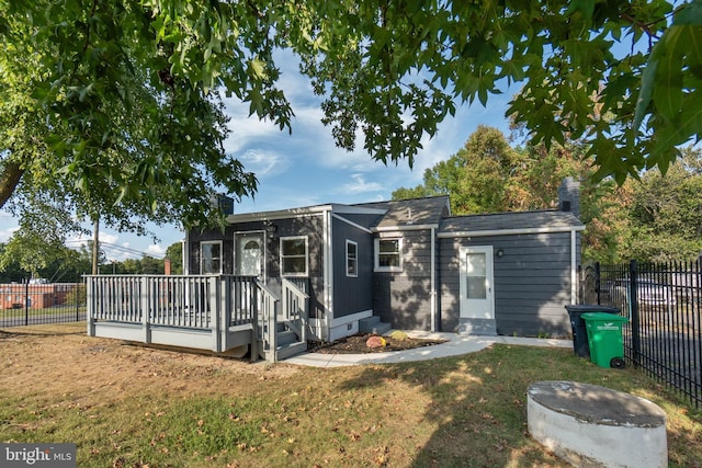 rear view of house with a lawn and a wooden deck