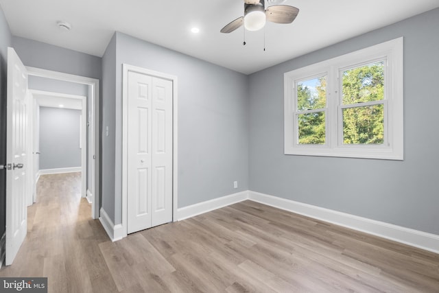 unfurnished bedroom with ceiling fan, a closet, and light wood-type flooring