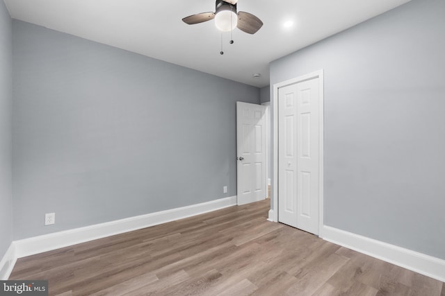 unfurnished bedroom with ceiling fan, a closet, and light wood-type flooring