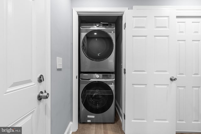 washroom featuring hardwood / wood-style floors and stacked washer / drying machine