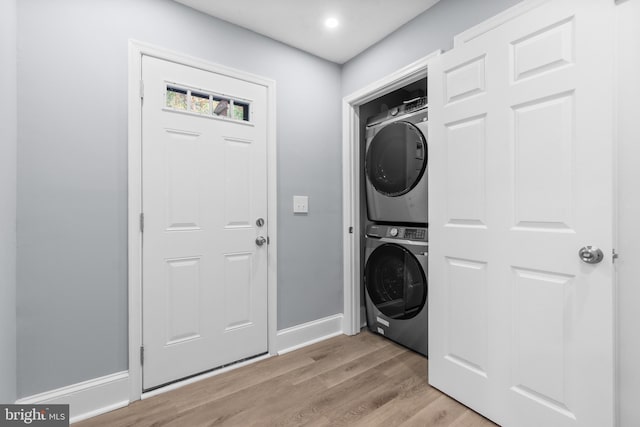 laundry room featuring light hardwood / wood-style floors and stacked washer / dryer