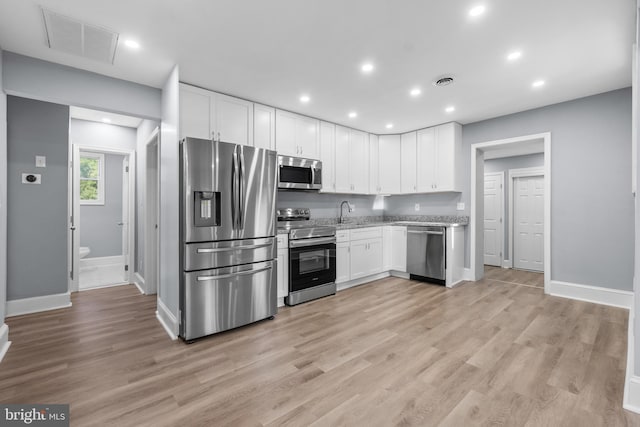 kitchen featuring light hardwood / wood-style floors, light stone counters, white cabinetry, and stainless steel appliances