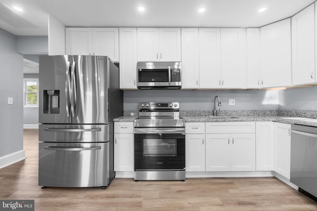 kitchen with sink, white cabinets, light hardwood / wood-style flooring, and appliances with stainless steel finishes