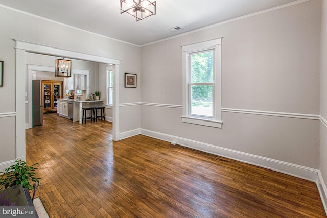 spare room with a notable chandelier, dark hardwood / wood-style floors, and ornamental molding