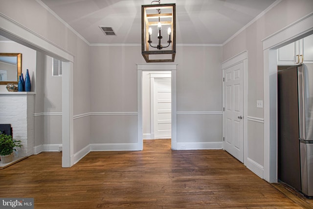 unfurnished dining area featuring crown molding, dark wood-type flooring, and a notable chandelier