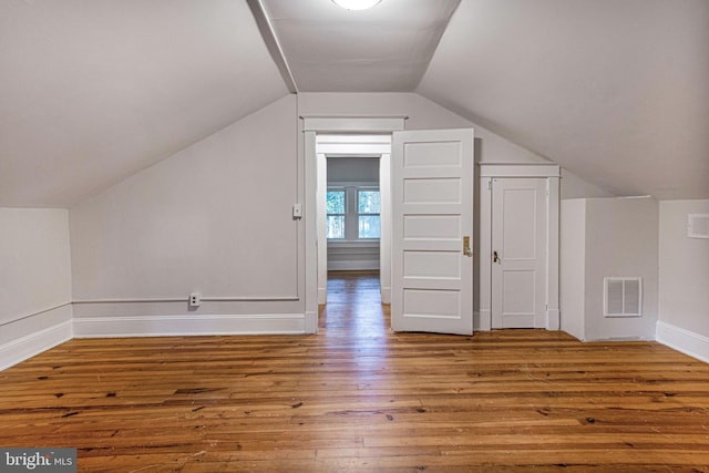 additional living space with hardwood / wood-style flooring and lofted ceiling