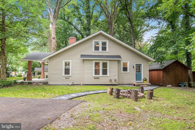 rear view of house with a storage unit and a yard