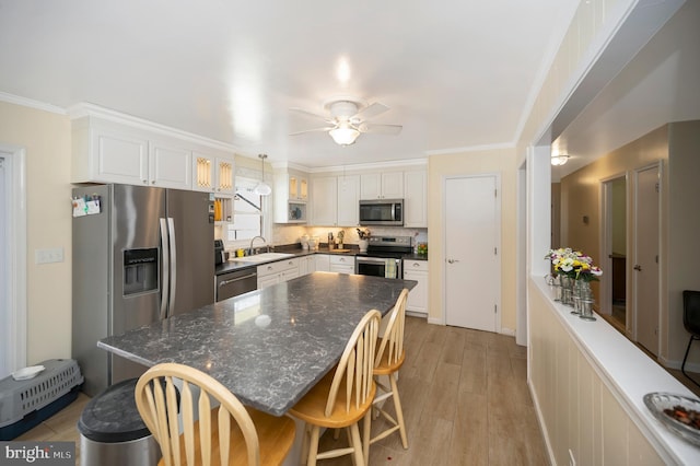 kitchen featuring white cabinetry, sink, ceiling fan, hanging light fixtures, and appliances with stainless steel finishes