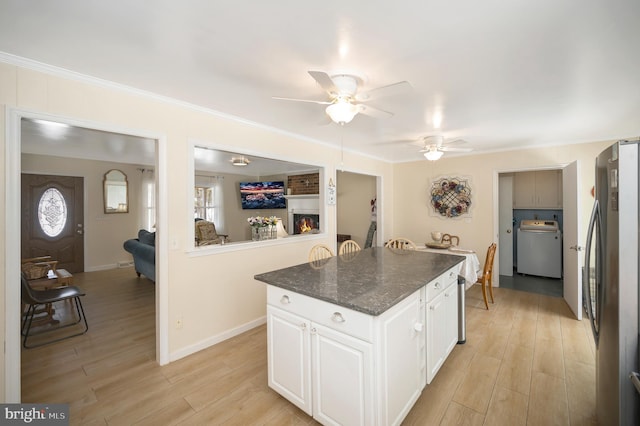 kitchen featuring a center island, ceiling fan, washer / dryer, white cabinetry, and stainless steel refrigerator