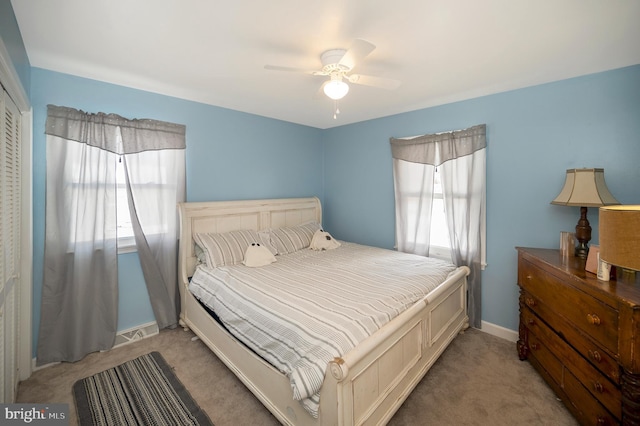 carpeted bedroom featuring multiple windows and ceiling fan