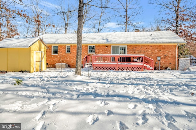 snow covered property with a storage shed and a wooden deck