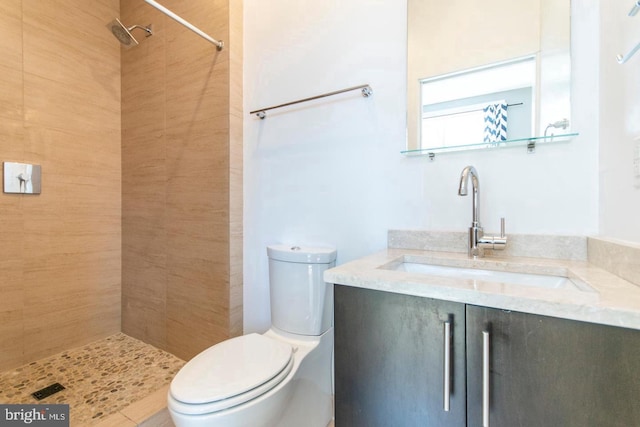 bathroom featuring vanity, toilet, and a tile shower