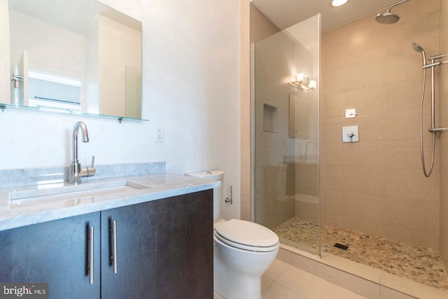 bathroom with tile patterned floors, vanity, toilet, and a tile shower