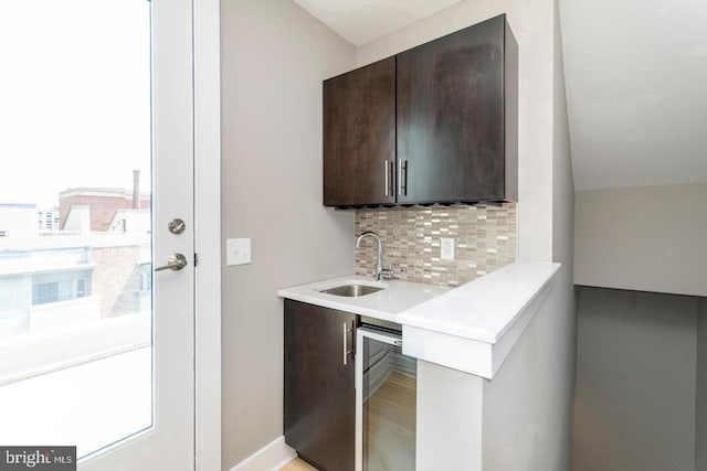 bar featuring dark brown cabinets, wine cooler, a wealth of natural light, and sink