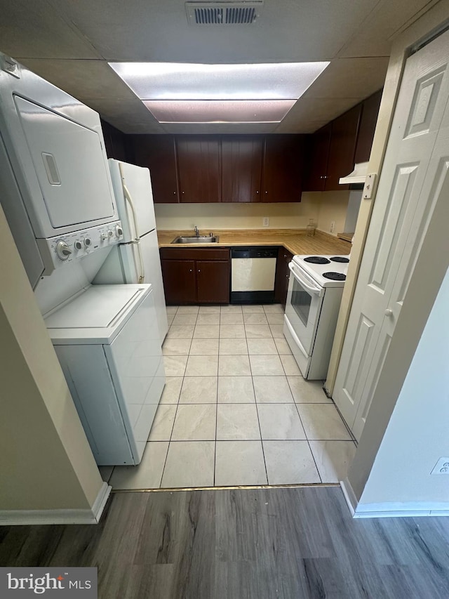 kitchen with sink, light tile patterned floors, stacked washer and clothes dryer, dishwasher, and white electric range