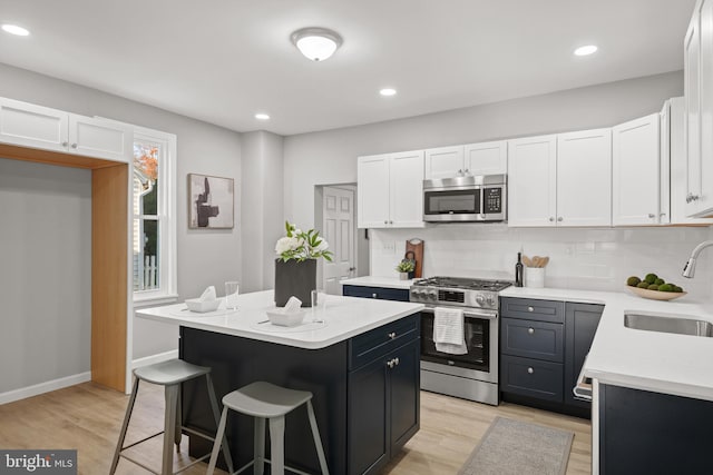 kitchen featuring white cabinets, appliances with stainless steel finishes, a kitchen island, and sink